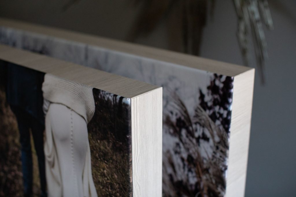 Two canvas prints with wooden edges are displayed side by side, showing partial images of people outdoors in natural, earthy tones.