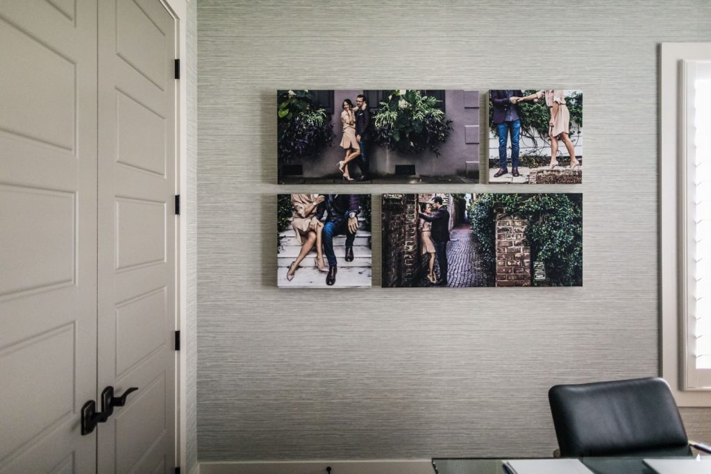 A light-colored home office wall with six photos of a couple walking outdoors, displayed in two rows above a black chair; a closed double door is on the left, and a window with white shutters is on the right.